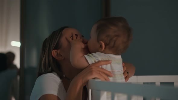 Young Mother and Baby in Crib at Night