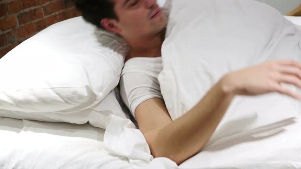 Young Man Waking Up from sleep in Bed, Morning