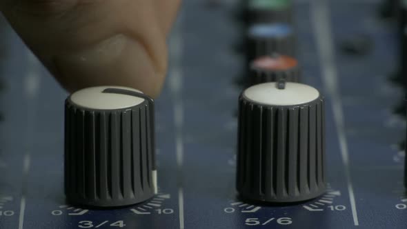 Male Fingers Turning Knobs on Audio Mixing Desk