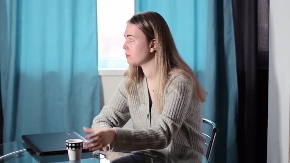 Young fair-haired woman is procrastinating instead of working at her laptop