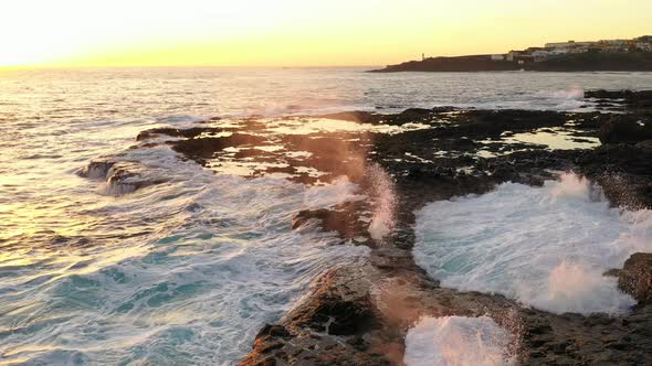 Waves Crashing Into Rocky Coastline At Sunset