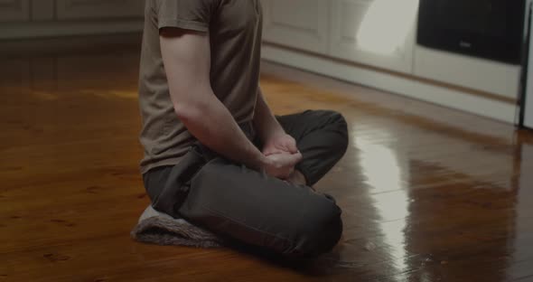 Side View of Young Yogi Sitting in Lotus Pose Meditating Alone at Kitchen Home