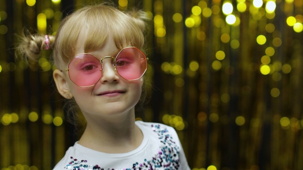 Child Kid Dancing, Claping Her Hands, Fooling Around. Girl Posing on Background with Foil Curtain