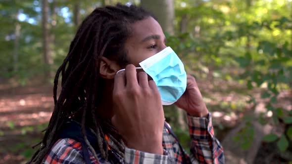 Young Gen Z Man Puts On Coronavirus Prevention Face Mask While Outdoors