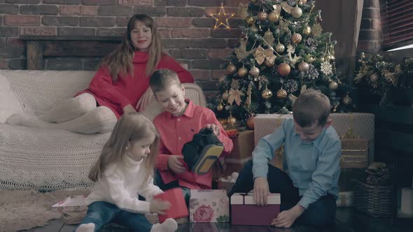 Small Children Open Christmas Present Boxes Woman Watches