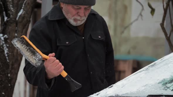 Bearded Senior Man Cleans Electric Automobile Windshield