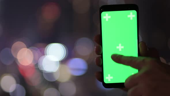 Hands Of Young Man Using Phone Against View Of The City At Night