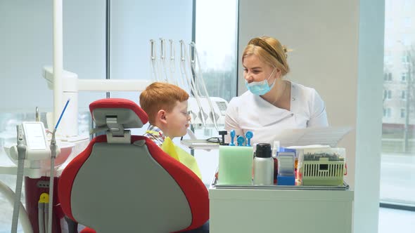 Female Dentist Writes on a Medical Card the Symptoms of a Boy Patient