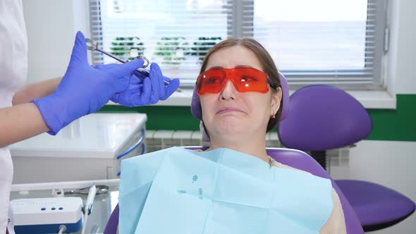 Portrait of Young Woman Afraid to Remove a Tooth Sitting in Dental Chair