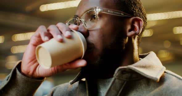 AfricanAmerican Man Drinks Coffee While Walking Around Business Center of City