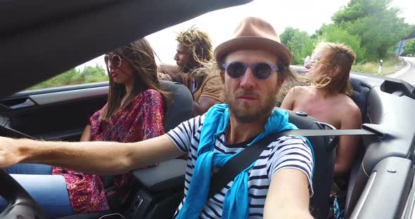 Bearded hipster man with a hat driving his friends in convertible