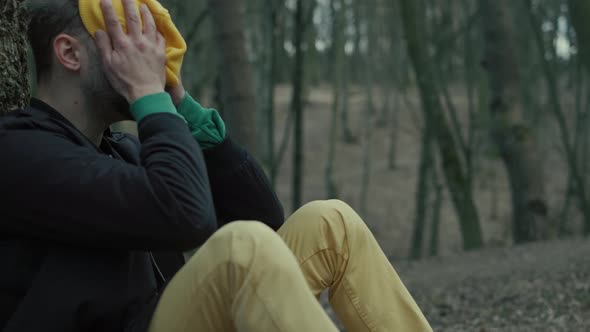 A Sad Man Is Sitting Alone on the Ground By a Tree, Suffering Emotional Pain and Thinling About