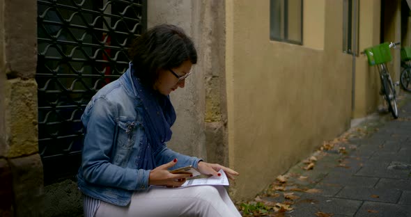 Businesswoman Looks at Sheets of Paper and Holds Smartphone