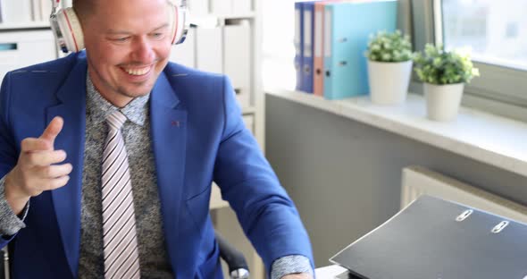 Young Man with Headphones Looking at Laptop Screen and Starting Dancing in Office  Movie