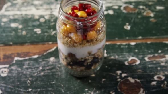 Yogurt with pomegranates and golden berries in glass jar 4k