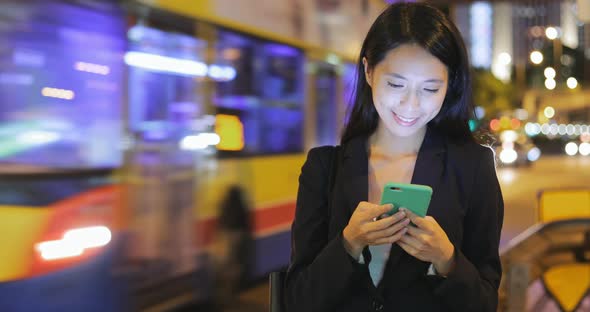 Business woman looking at mobile phone at night 