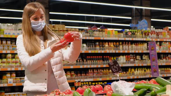 A Woman Chooses Ripe Juicy Tomatoes in the Supermarket