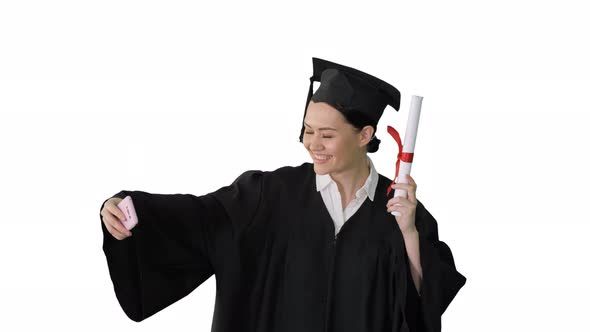 Happy Female Graduate Holding Diploma and Making Selfie on Her Phone on White Background.
