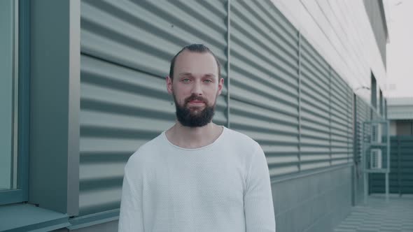 Smiling Bearded Millennial Hipster with Blue Eyes Looking at Camera