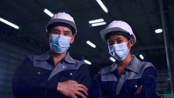 team of engineers wearing medical face masks working together in factory under COVID-19 situation