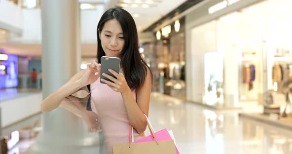 Woman use of mobile phone and carrying paper bags