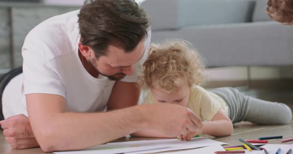 Close Up of a Little Girl and Her Father Who are Drawing on the Floor Grey Sofa in the Background