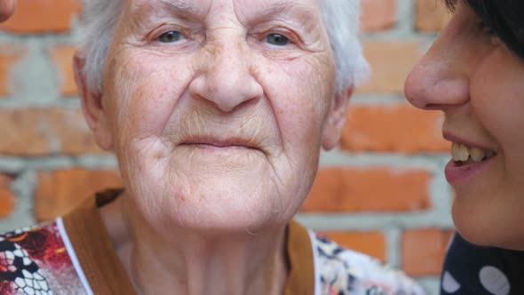 Young Man and Adult Woman Kissing Their Beloved Grandmother on Cheeks