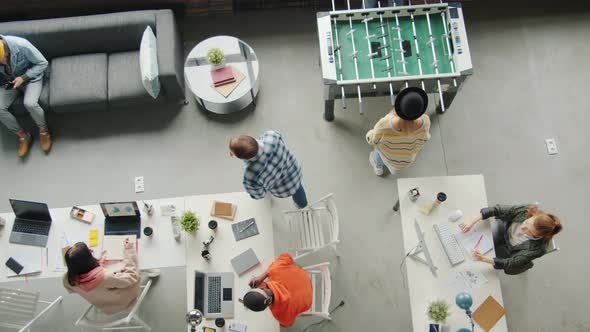 Top View of Modern Business Men and Women Working and Relaxing Playing Table Soccer in Office