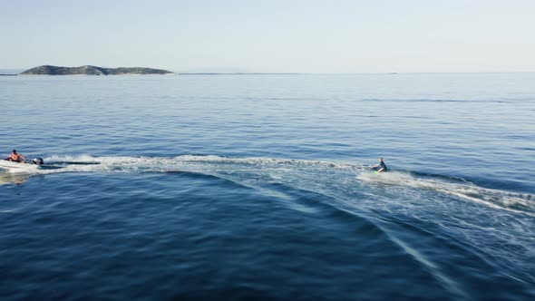 Drone view of kid doing water ski in the sea.