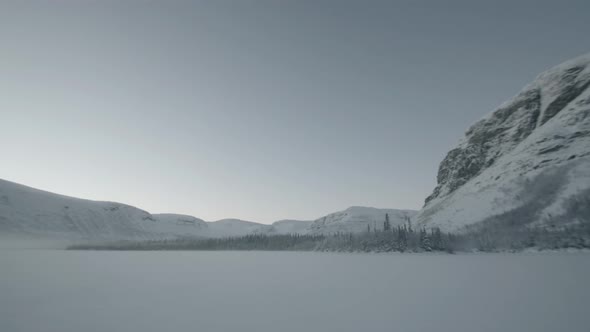 Beautiful View of a Field with Pure Snow Surrounded By a Snowcovered Forest and Mountain Ranges on a