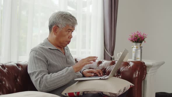 Senior man typing chatting on laptop computer with happy