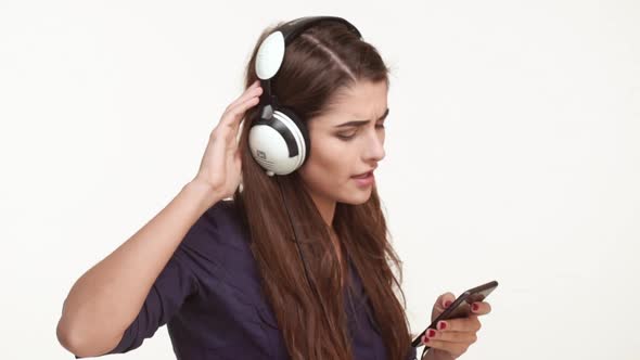 Active Young Caucasian Female with Long Brown Hair Wearing Dark Blue Shirt Listening Music From