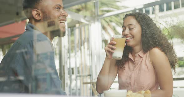 Happy diverse couple spending time together at cafe, drinking coffee and talking