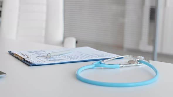 Unrecognizable Doctor Taking Stethoscope from the Desk