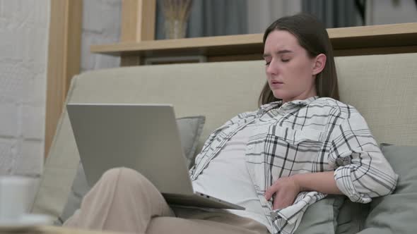 Tired Young Woman Sitting on Sofa and Having Back Pain 