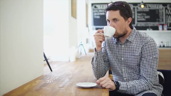 An Adult Man Enjoys the Taste of the American, Which He Drinks in a Cafe