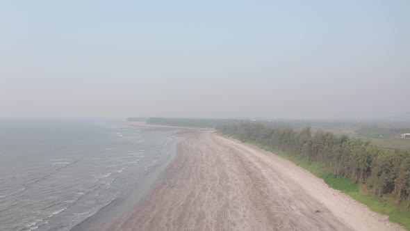 descending drone shot over empty sandy beach on a hazy day