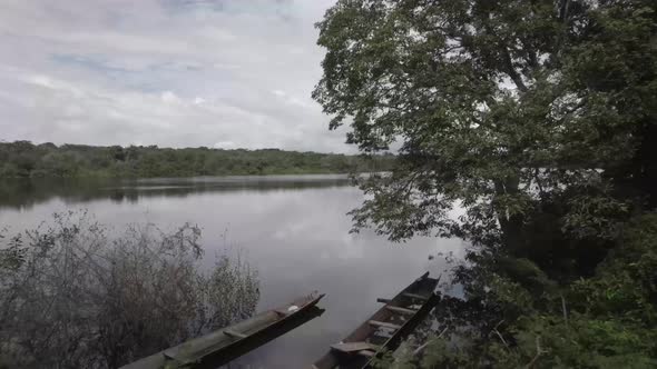 View Of Calm Lakeshore With Broken Wooden Boats In Colombian Amazon Forest. Dolly Shot