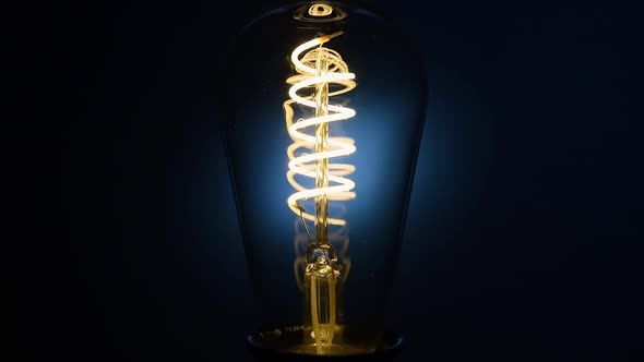 Electric Vintage Edison Light Bulb with a Spiral Flashing on a Blue Background