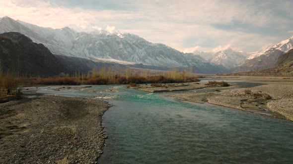 Aerial Low Flying Along Winding River Rising To Reveal Sweeping Landscape Of Ghizer Valley Of Gilgit