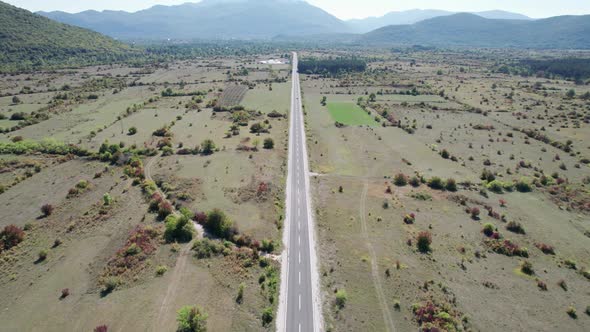 Aerial View Empty Asphalt Road on the Plateau Between Green Fields Highland Way