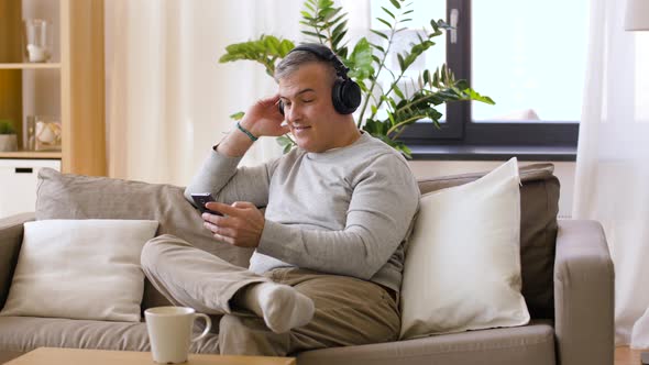 Man with Smartphone and Headphones at Home