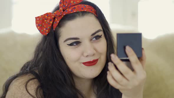 Portrait of Attractive Young Plus Size Girl Doing Make-up Looking in the Mirror Close-up. Plump