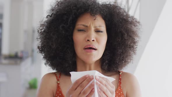 Woman with tissue sneezing at home