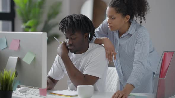 Positive Young Woman Talking with Cheerful Man Surfing Internet in Home Office