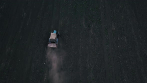 Aerial view of a farmer on a green tractor plowing the dusty arid soil. Agribusiness in the spring