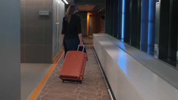 Woman with trolley case in the hotel hallway