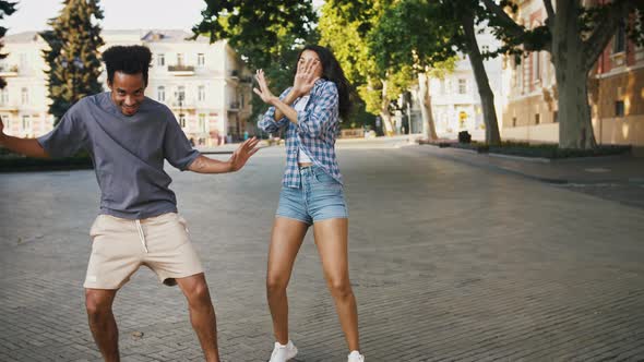 Darkskinned Man and Woman are Smiling and Dancing at City Square