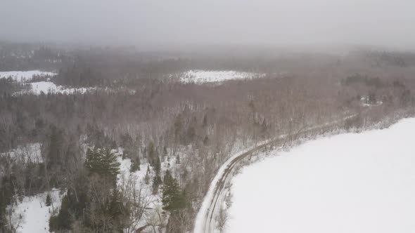 Aerial flying high above Winter forestry view with thick snowfall