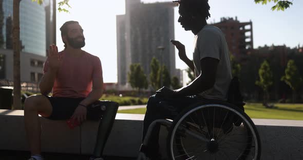 Multiethnic friends with disability greeting each other at city park
